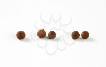 five berries of allspice on white background