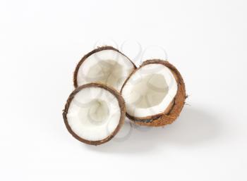 three fresh coconut halves on white background