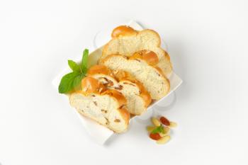slices of sweet braided bread with almonds and raisins on white plate