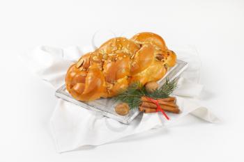 loaf of Christmas sweet braided bread on wooden cutting board and white napkin
