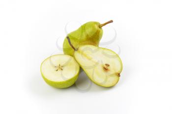 whole and halved ripe pears on white background