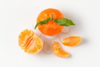 whole tangerine with separated segments on white background