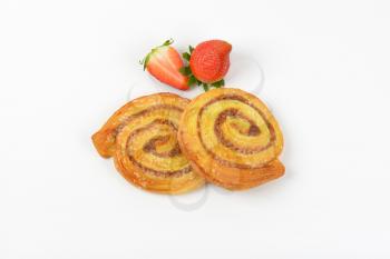 sweet cinnamon rolls and strawberries on white background