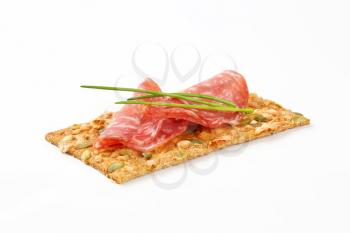 pumpkin seed cracker with thin slices of dry salami sausage