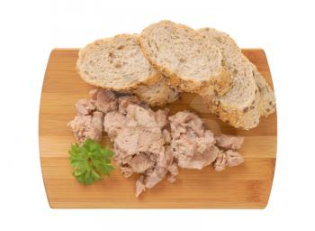 pieces of canned tuna and sliced seeded bread roll on cutting board