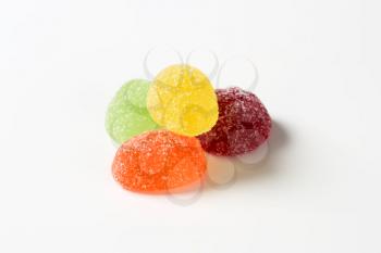 four fruit jelly candies coated with sugar on white background