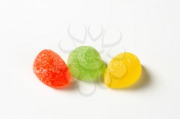 three fruit jelly candies coated with sugar on white background