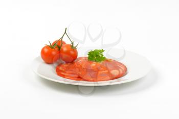 plate of chorizo salami and cherry tomatoes on white background