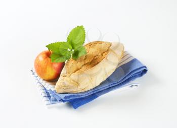 diamond shaped rustic bread roll and fresh apple on striped dishtowel