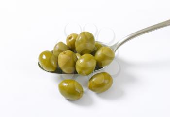 spoon of green olives on white background