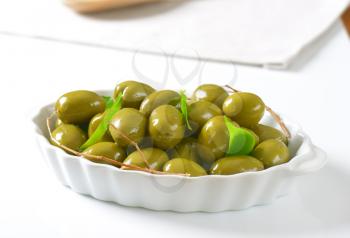 bowl of green olives on white background - close up