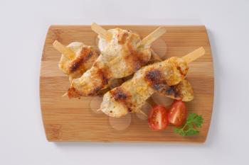 grilled chicken skewers on wooden cutting board