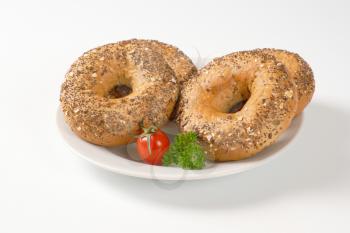 fresh bagels topped with seeds on white plate