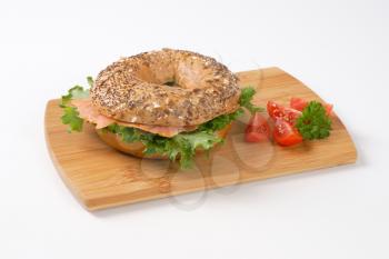 bagel sandwich with smoked salmon on wooden cutting board