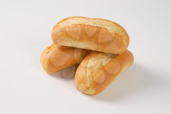 three freshly baked mini baguettes on white background