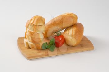 whole and sliced mini baguettes on wooden cutting board