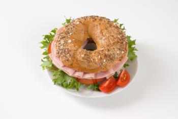 bagel sandwich with ham on white plate