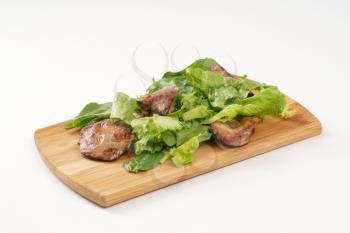 pan fried liver with greens on wooden cutting board