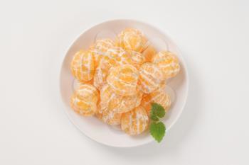 plate of peeled tangerines on white background