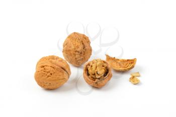 whole and cracked walnuts on white background