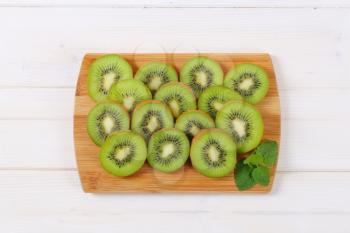 slices of ripe kiwi arranged on wooden cutting board