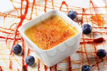 Creme brulee garnished with caramelized sugar decoration and blueberries