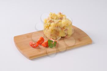 crushed potatoes with bacon on wooden cutting board