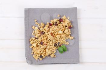 pile of morning granola with hazelnuts, raisins and cranberries on grey place mat