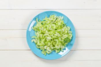 plate of chopped celery stems on white wooden background