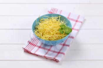 bowl of dry soup noodles on checkered dishtowel