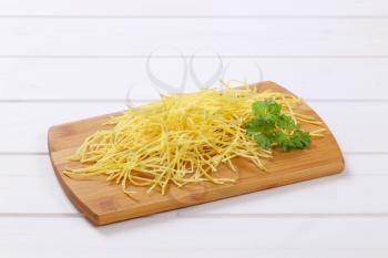 heap of dry soup noodles on wooden cutting board