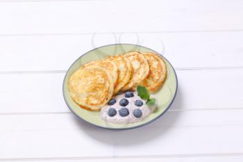 plate of american pancakes with yogurt and fresh blueberries on white wooden background