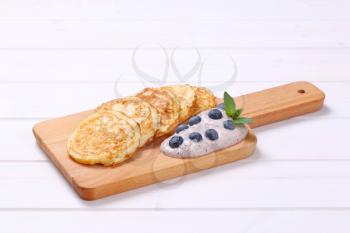 american pancakes with yogurt and blueberries on wooden cutting board