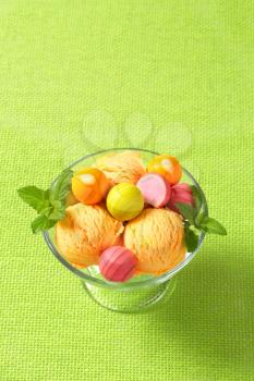 Fruit-flavored ice cream and white chocolate bonbons with fruit ganache filling on green background