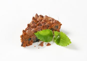 slice of homemade chocolate cake with mint on white background