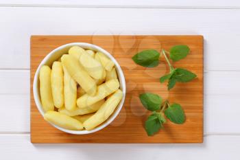 bowl of cooked potato cones or gnocchi on wooden cutting board