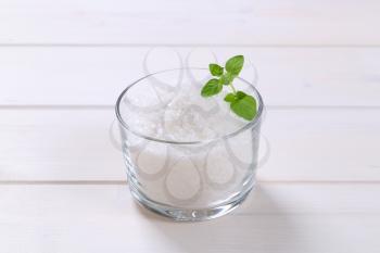 glass of coarse grained sea salt on white wooden background