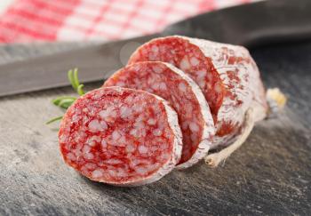 French dry cured sausage with rosemary on black cutting board