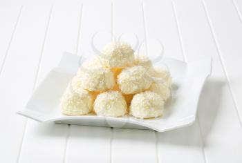 Pile of coconut snowball truffles on square plate