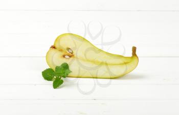 half a ripe pear on white wooden background