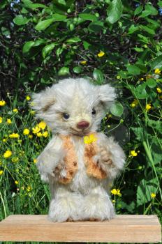 Handmade, the sewed toy: teddy-bear Sema on a little board among flowers under green plum