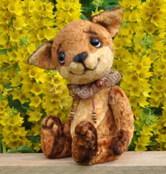 Ron fox cub on a board among flowers. Handmade, the sewed plush toy