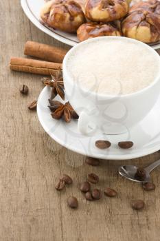 cup of coffee with beans and cakes on wood background