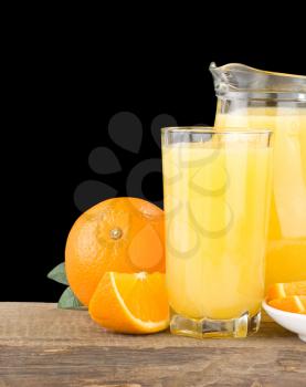 orange juice in glass and jug isolated on black background