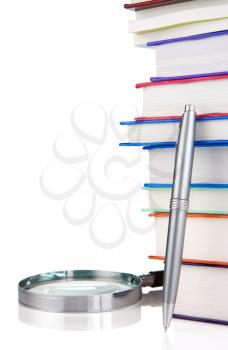 pile of new books, pen and magnifying glass isolated on white background