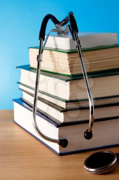 pile of book and stethoscope on blue background