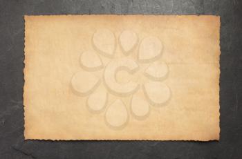 old retro aged paper parchment on slate stone background, top view