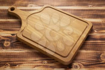 cutting board at rustic wooden table plank background, front view