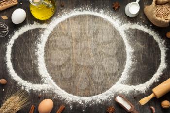 wheat flour and bakery ingredients on wooden background, top view