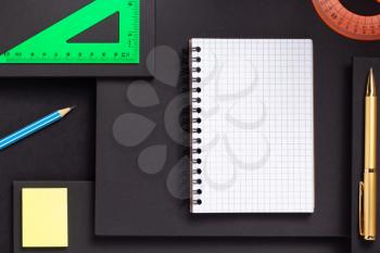 school accessories and office supplies at abstract black paper background